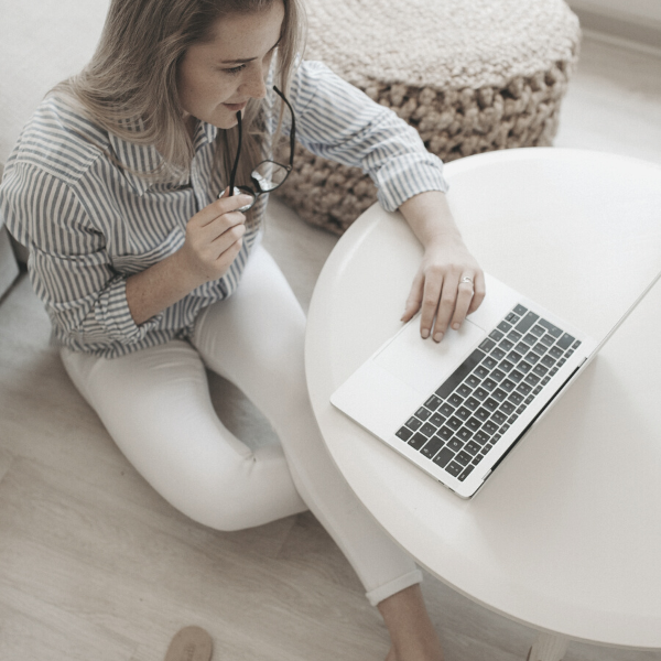 A woman sitting on the ground with a laptop on a coffee table